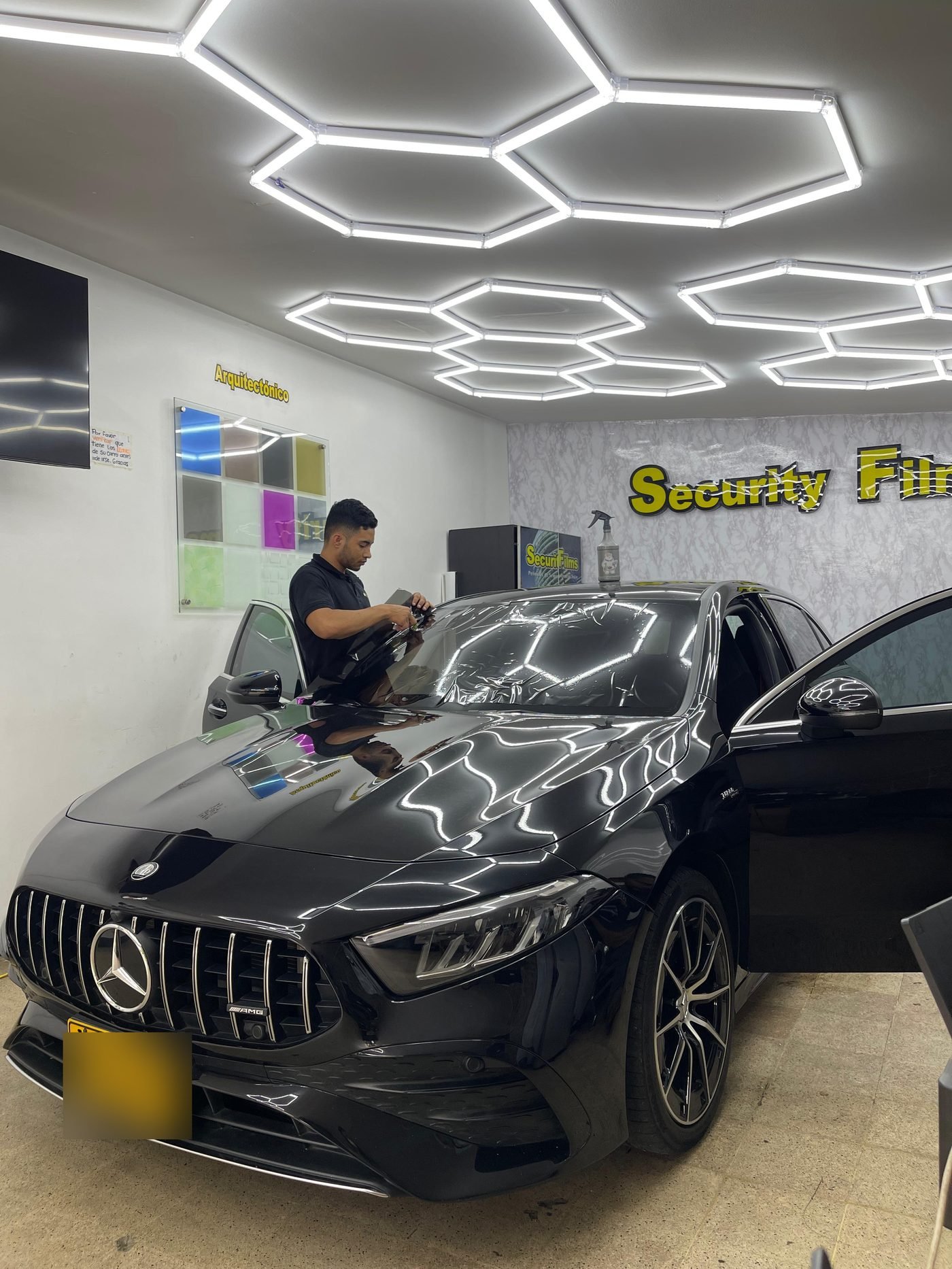 Técnico de Security Films trabajando sobre un Mercedes-AMG negro en el taller de Barrio Colombia
